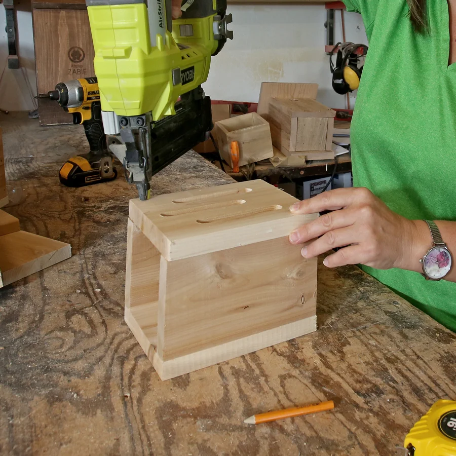 Une femme utilise une perceuse pour construire une boîte dans le cadre d'un projet de refuge pour la faune dans le jardin.